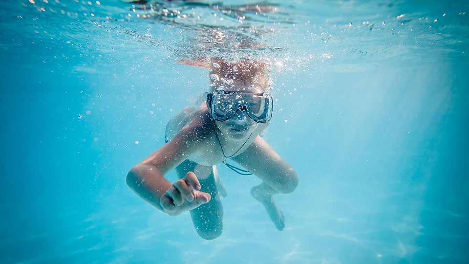 Pojke som badar med cyklop under vatten i bassäng