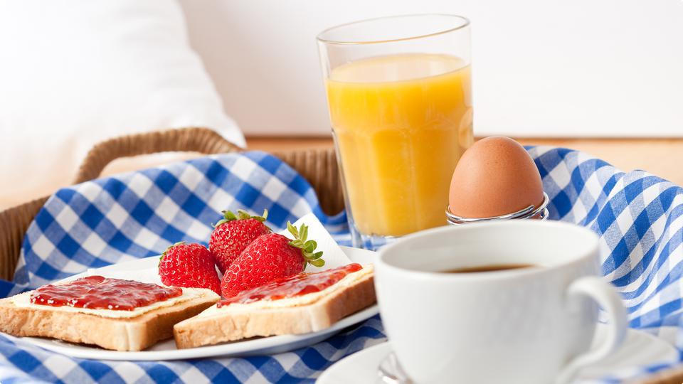 Lyxig frukostbricka med bröd, kaffe, ägg och juice.