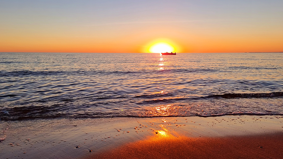 Siluett av båt i solnedgången vid havet i Mellbystrand.