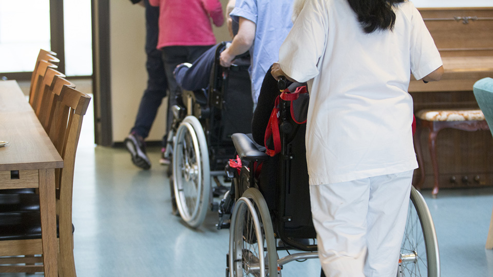 Vårdpersonal skjutsar äldre i rullstol