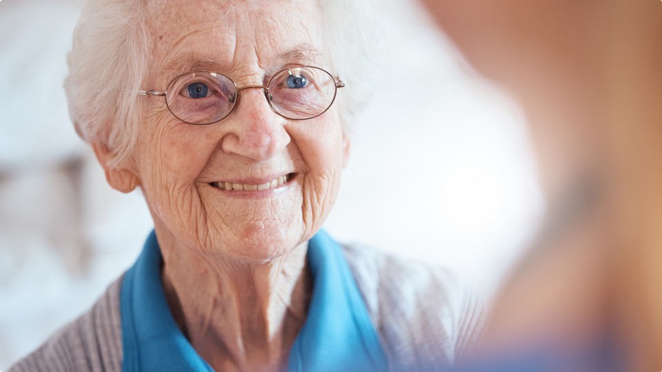 Leende äldre kvinna med glasögon.