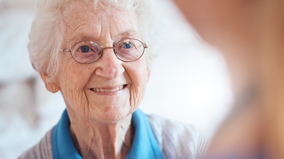 Leende äldre kvinna med glasögon.