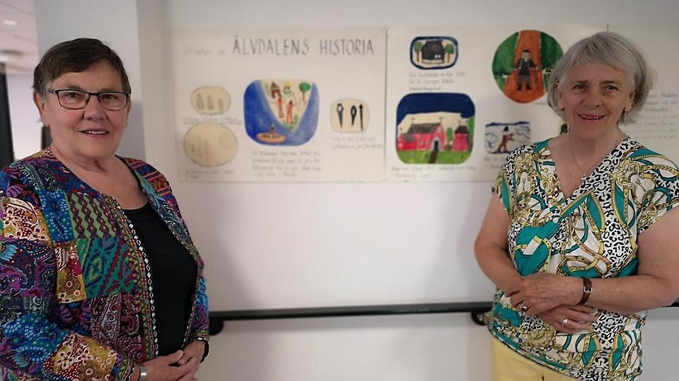 Två kvinnor står framför en teckning som är en del av en utställning om Älvdalens historia