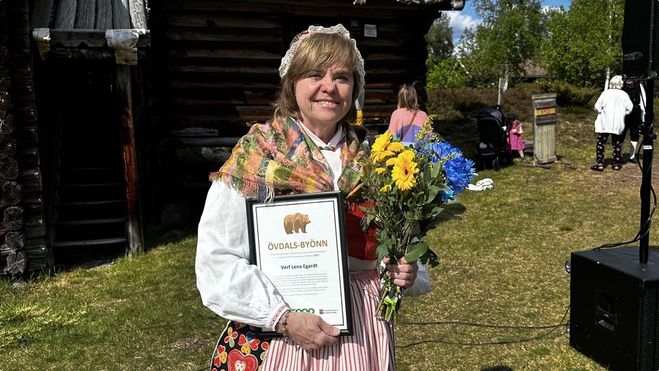Pristagaren av Övdalsbyönn Lena Egardt iklädd älvdalsdräkt på Rots skans. Hon håller ett diplom och blommor. 