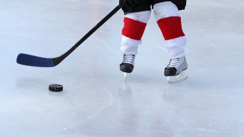 Ishockeyspelare med klubba och puck på isen.